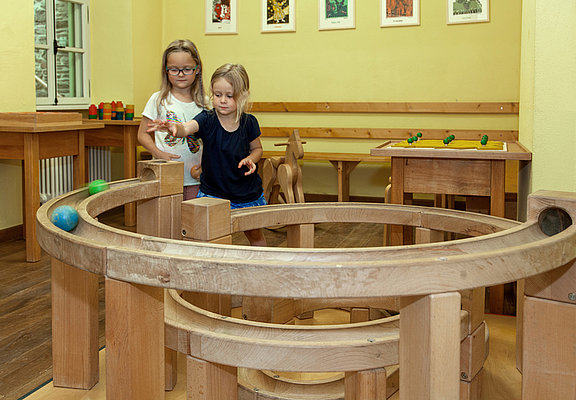Das Bild zeigt zwei Mädchen, die mit einer Kugelbahn im Spielzimmer des Hunsrücker Holzmuseums spielen.
