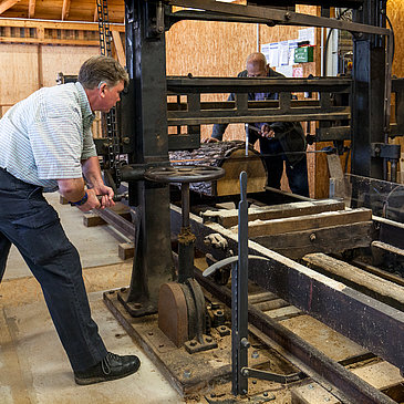 Das Bild zeigt einen Mann, der im Drechselraum des Hunsrücker Holzmuseum eine alte Maschine bedient im Rahmen einer Gästeführung.