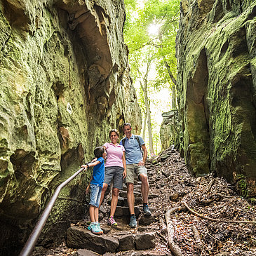Das Bild zeigt eine Familie auf dem Wanderweg Teufelsschlucht zwischen Felsen.